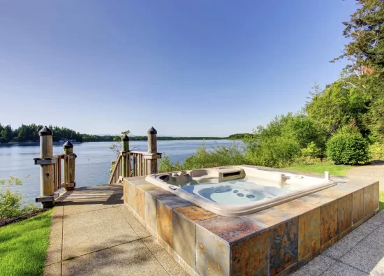 Backyard area with  awesome water view and hot tub with tile trim and concrete floor.
